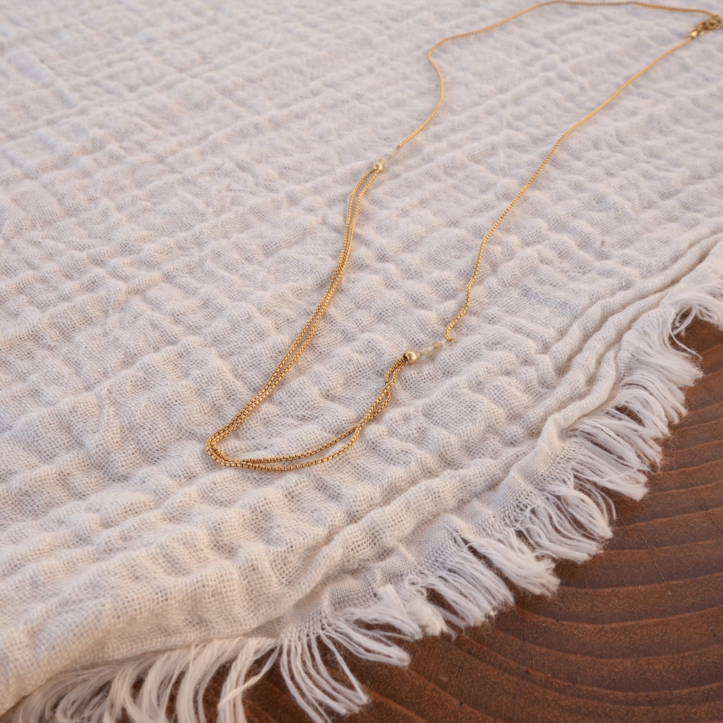 necklace with gold-fill chain and citrine faceted stones on a white cloth