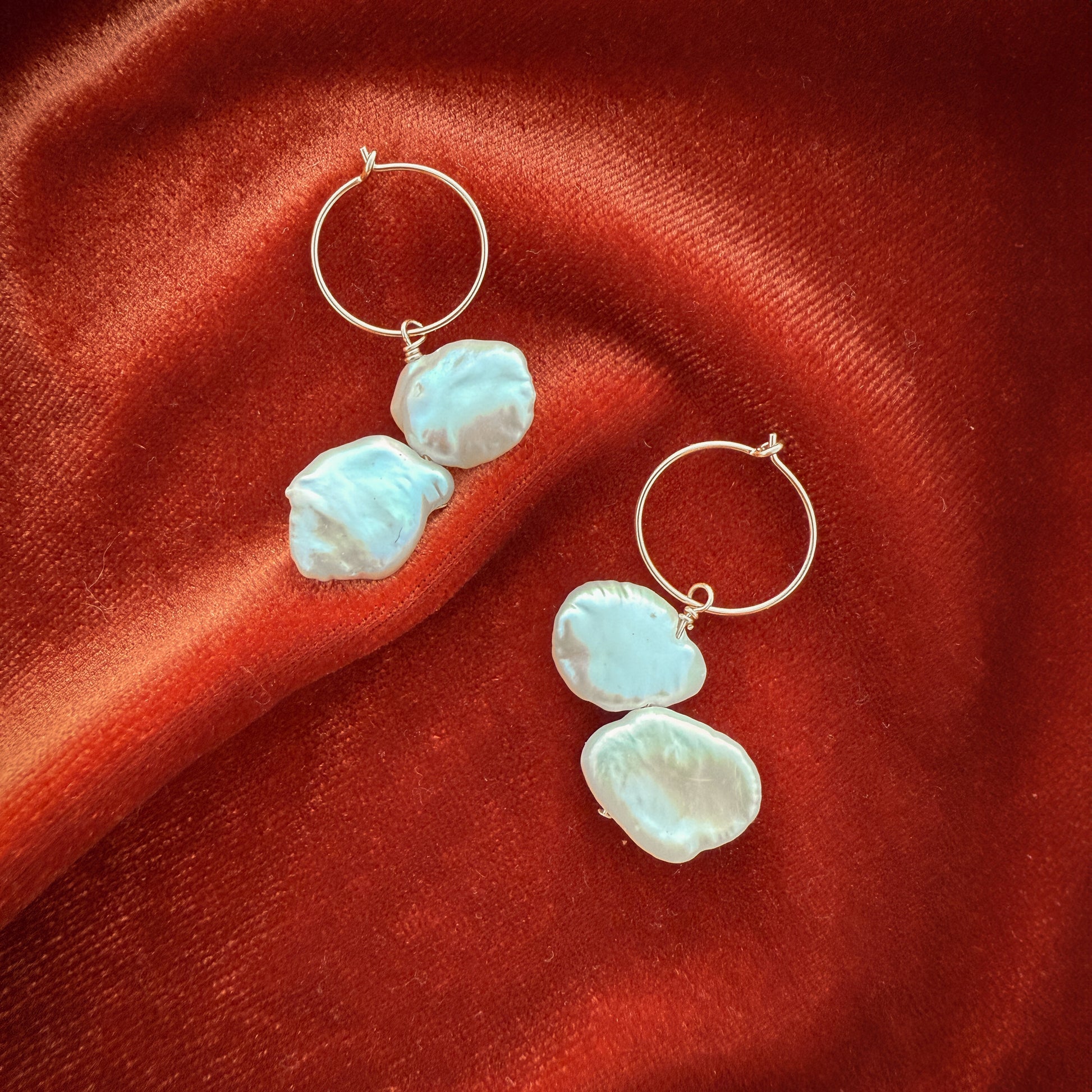 gold-filled hoop earrings with dangling keshi pearls on a red cloth
