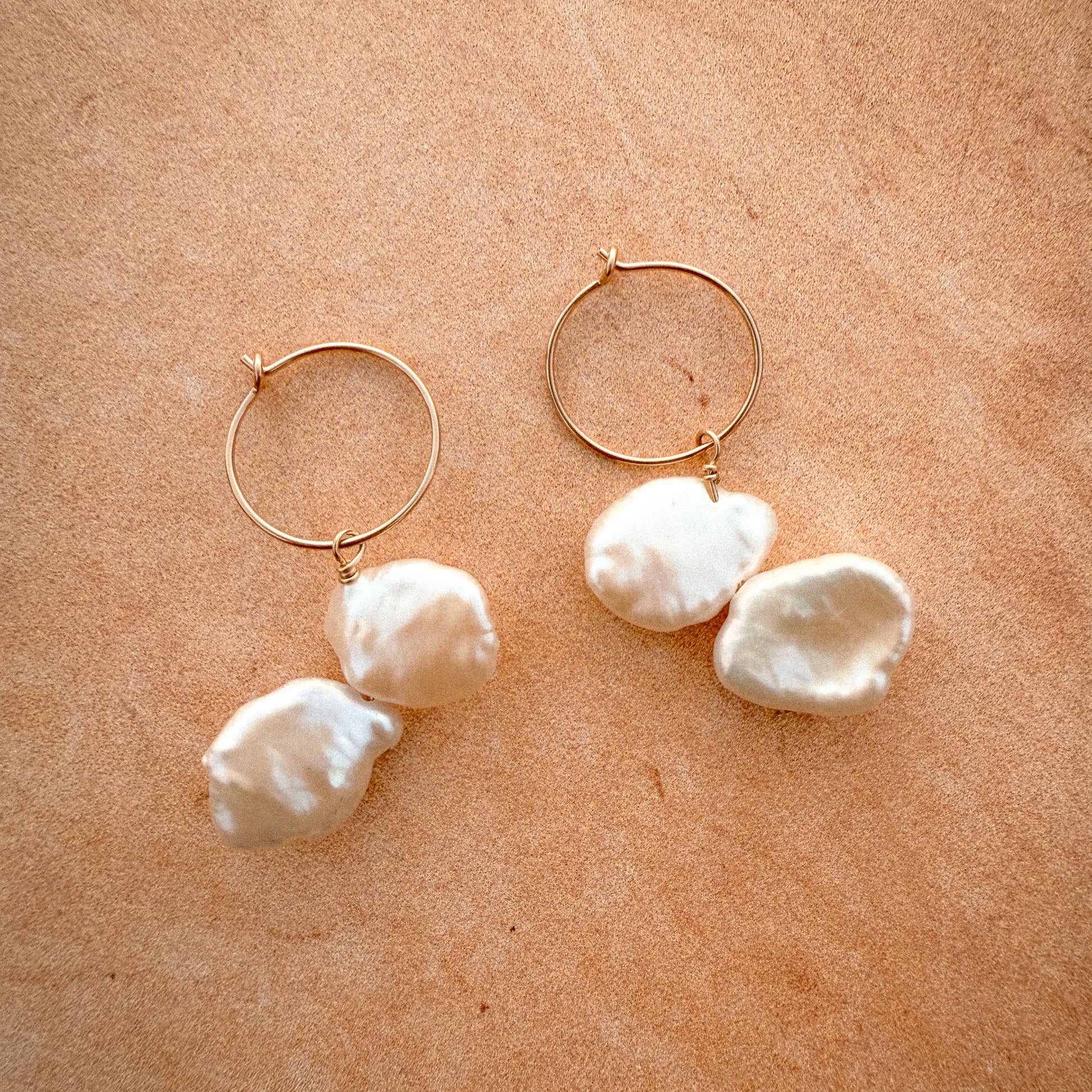 gold-filled hoop earrings with dangling keshi pearls on a brown surface