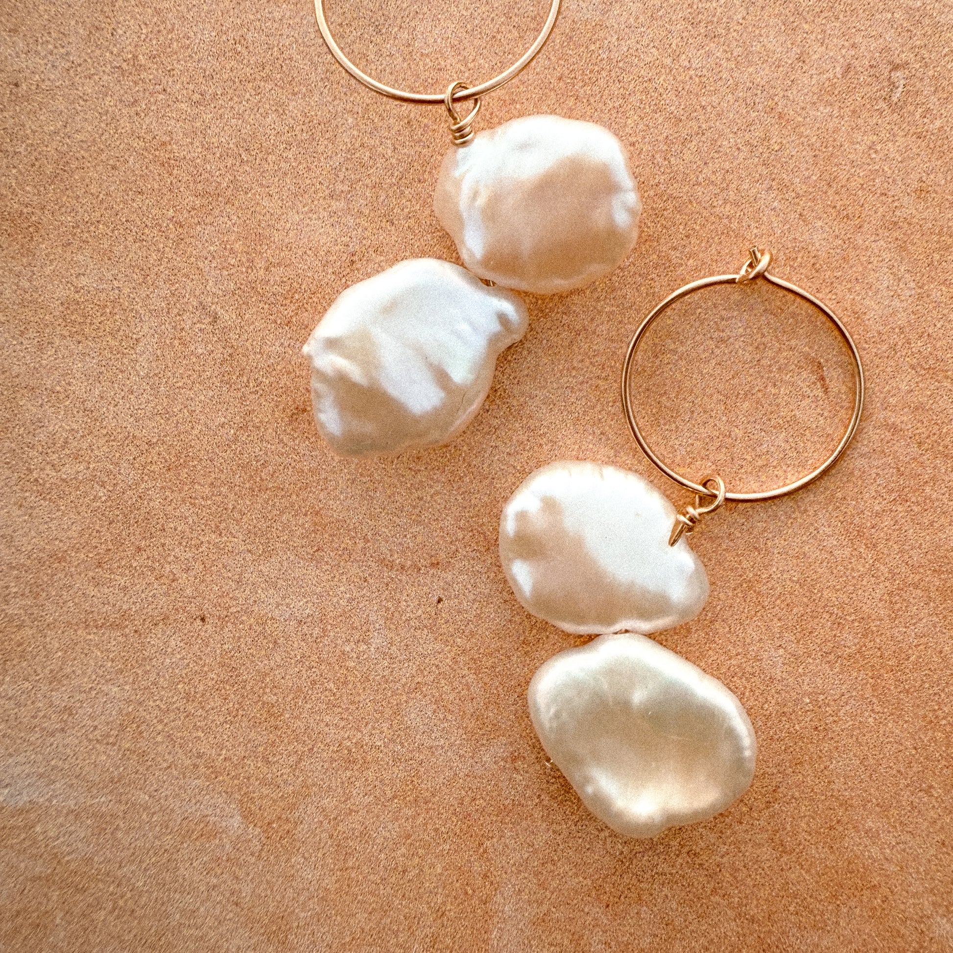close up of gold-filled hoop earrings with dangling keshi pearls