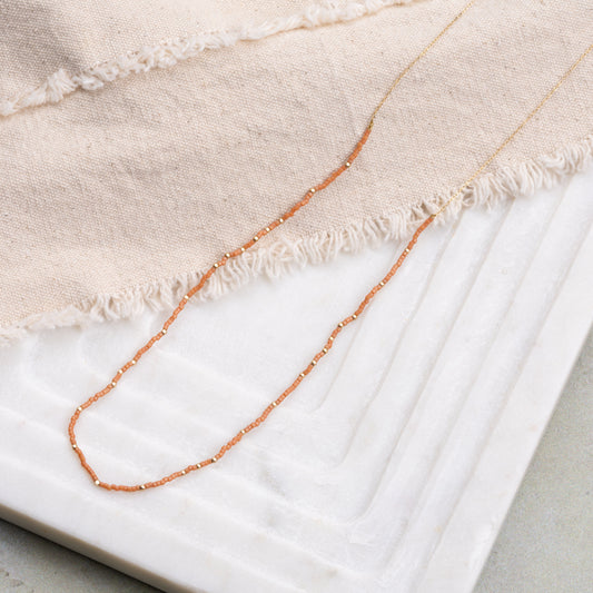 necklace with brown miyuki glass beads on a beige cloth and white tray