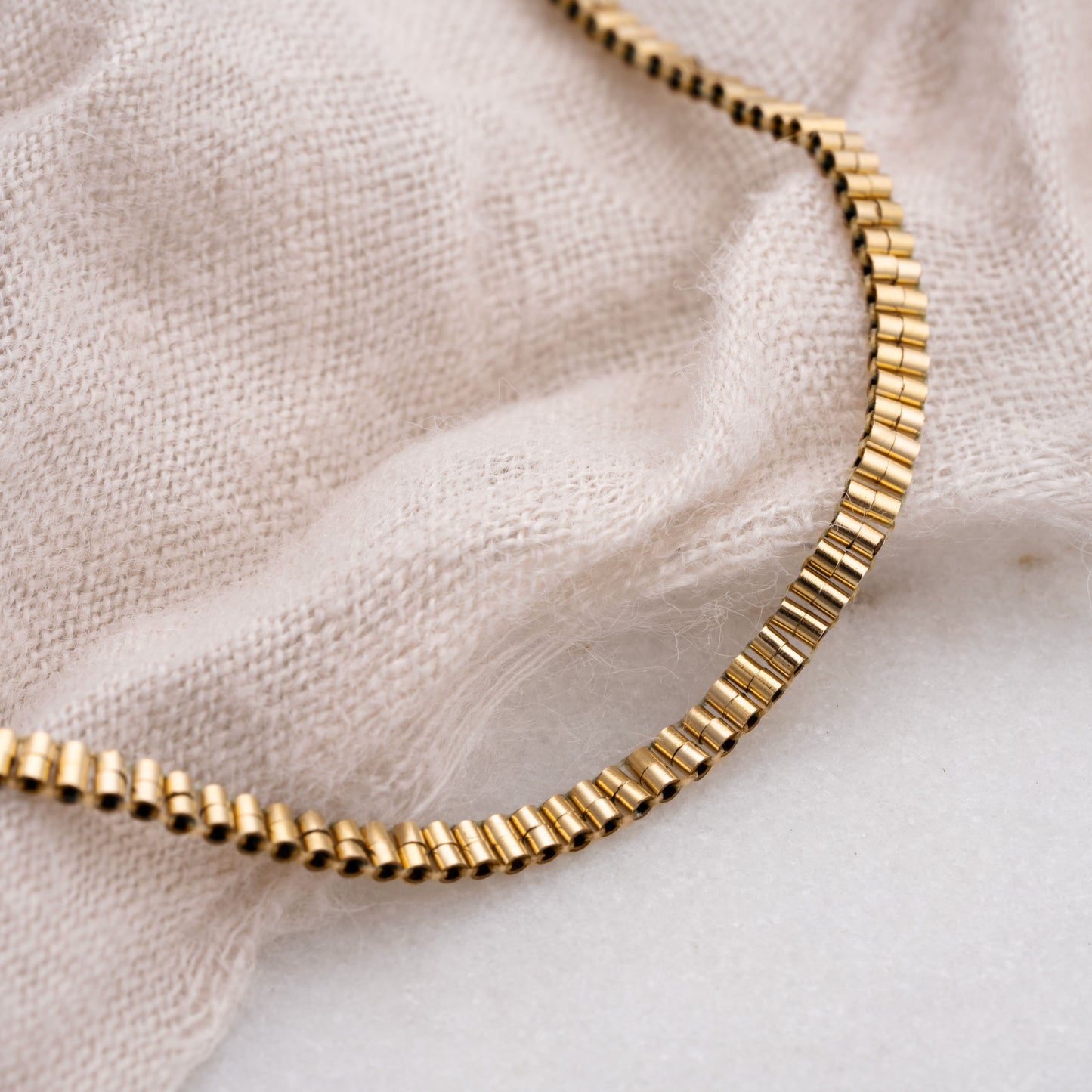 close up of gold-filled beaded bracelet on white cloth