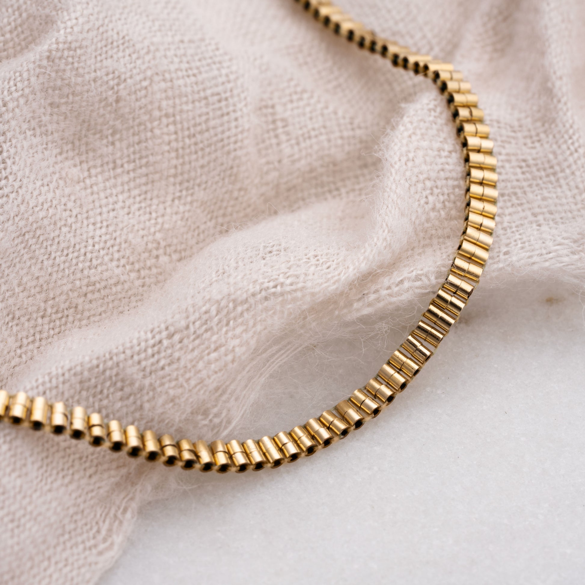 close up of gold-filled beaded bracelet on white cloth
