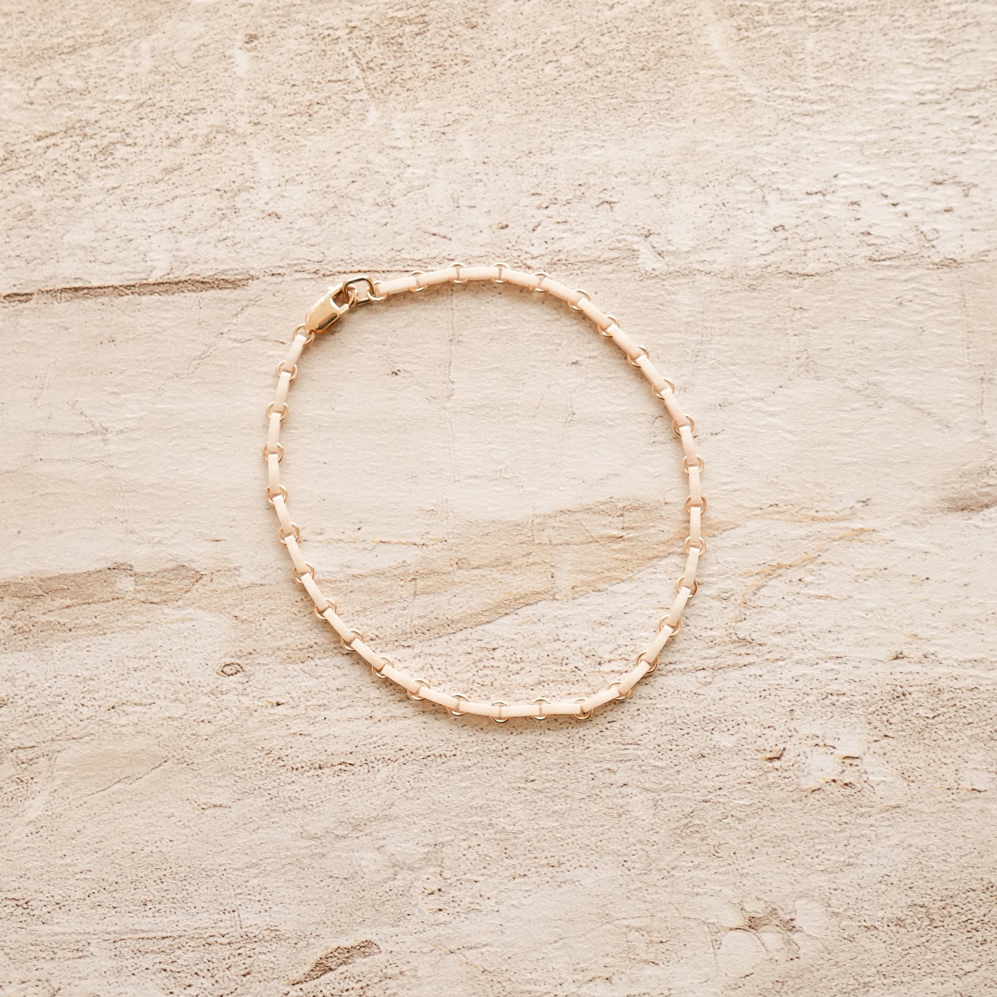 white bracelet with Japanese glass beads and circle chain links on a stone surface