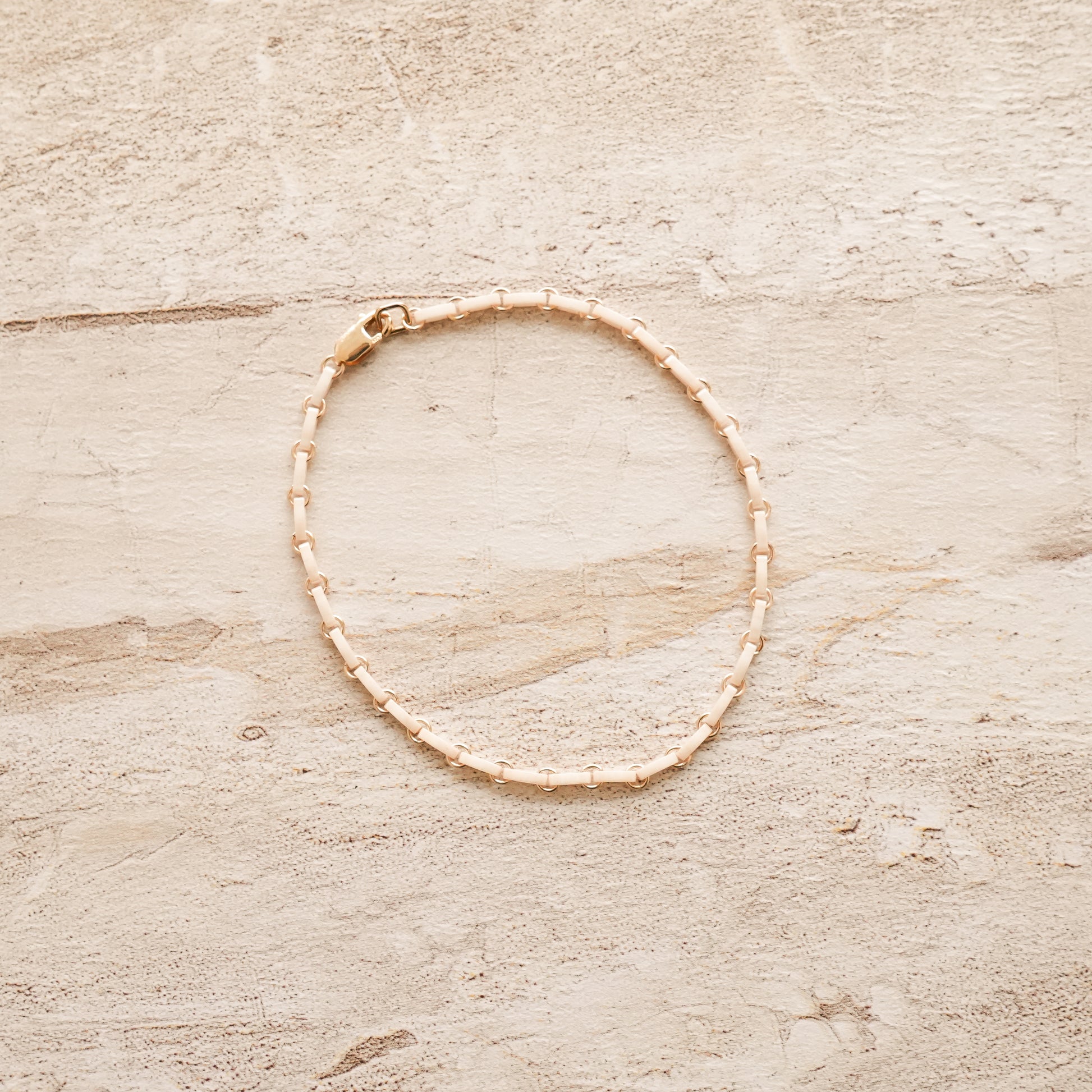 white bracelet with Japanese glass beads and circle chain links on a stone surface