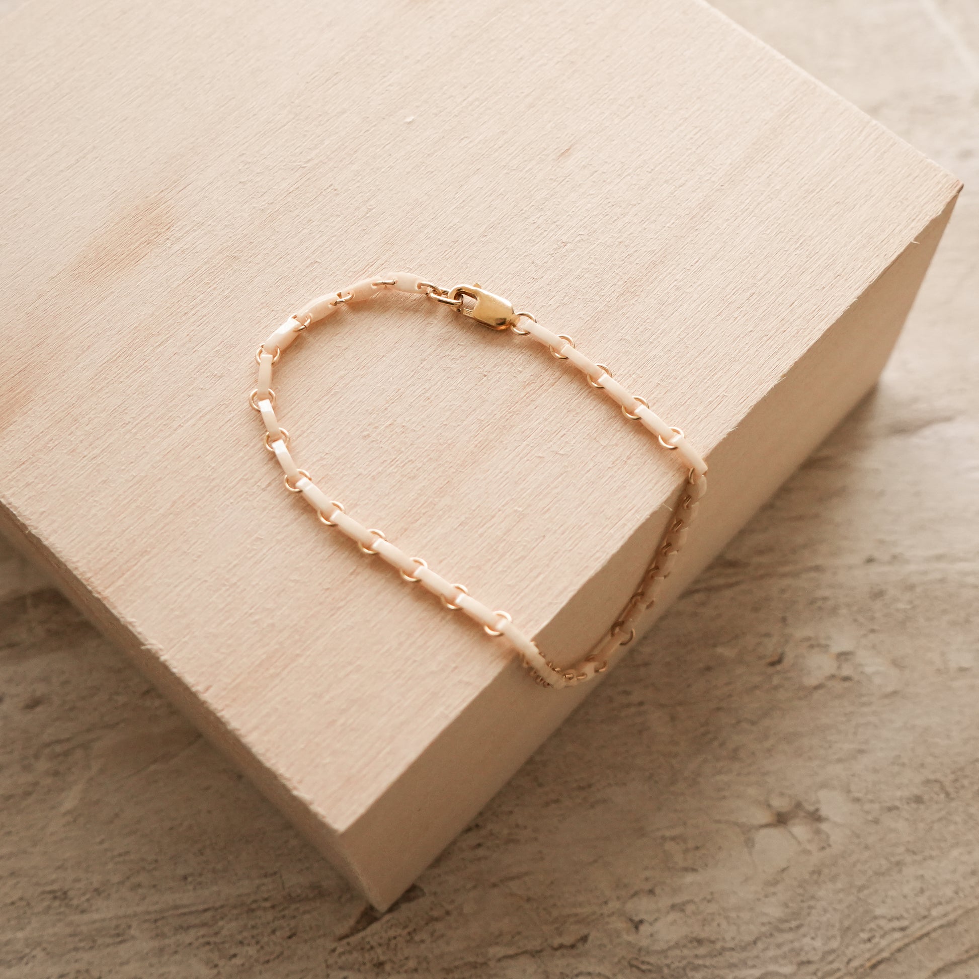 white bracelet with Japanese glass beads and circle chain links on a wooden block
