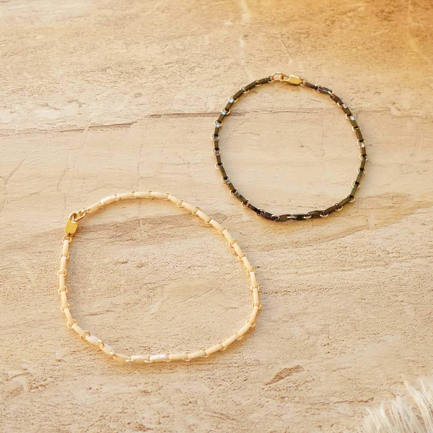 black and white bracelets with Japanese glass beads and circle chain links on a stone surface