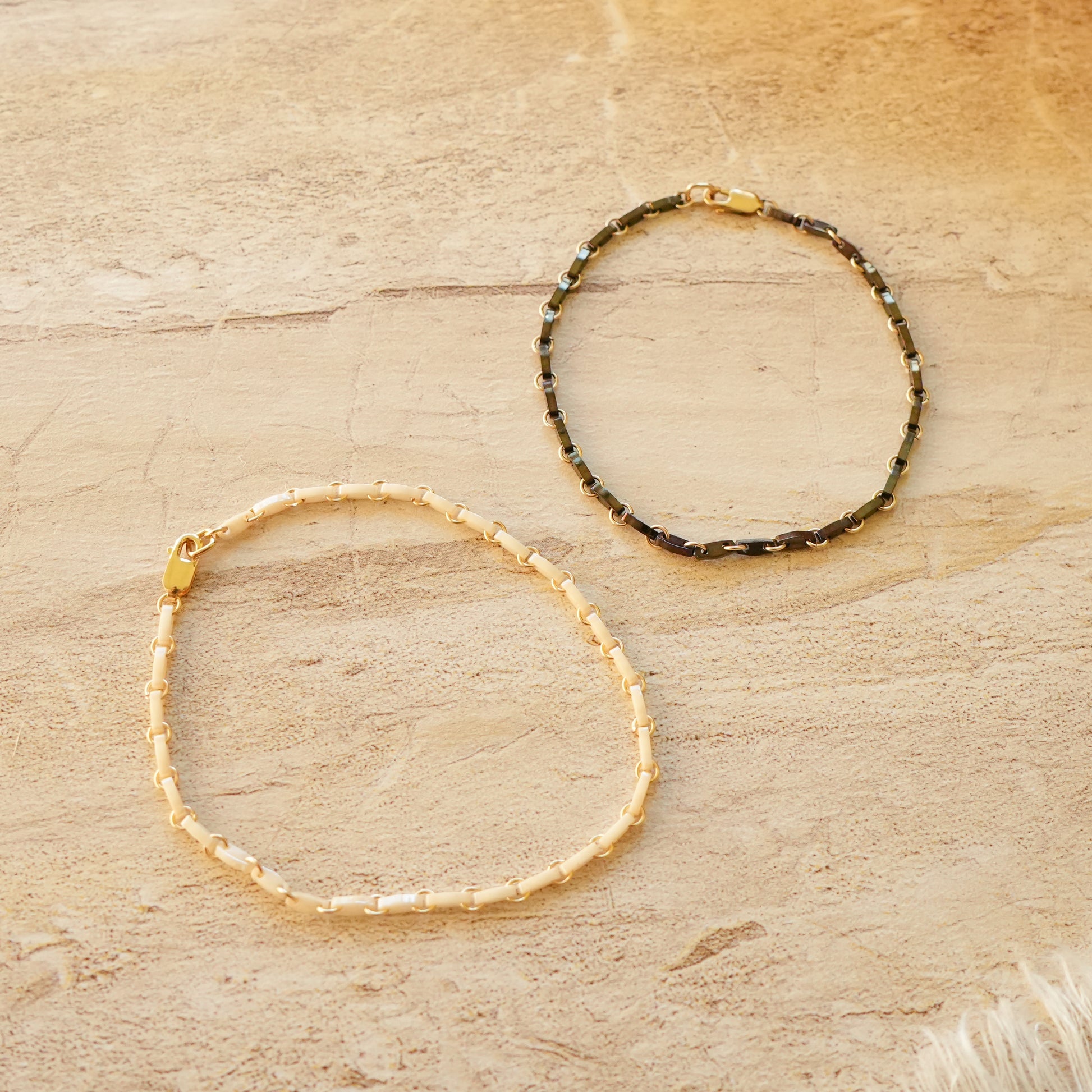 black and white bracelets with Japanese glass beads and circle chain links on a stone surface