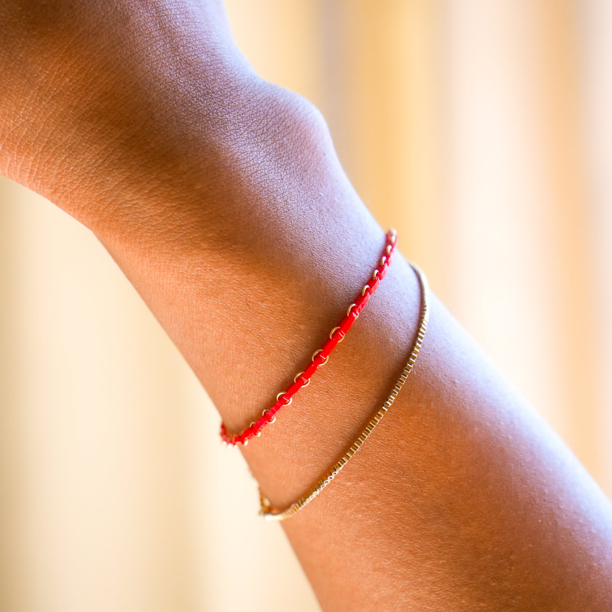 woman's wrist with red Japanese glass bead bracelet and gold-filled dainty bracelet