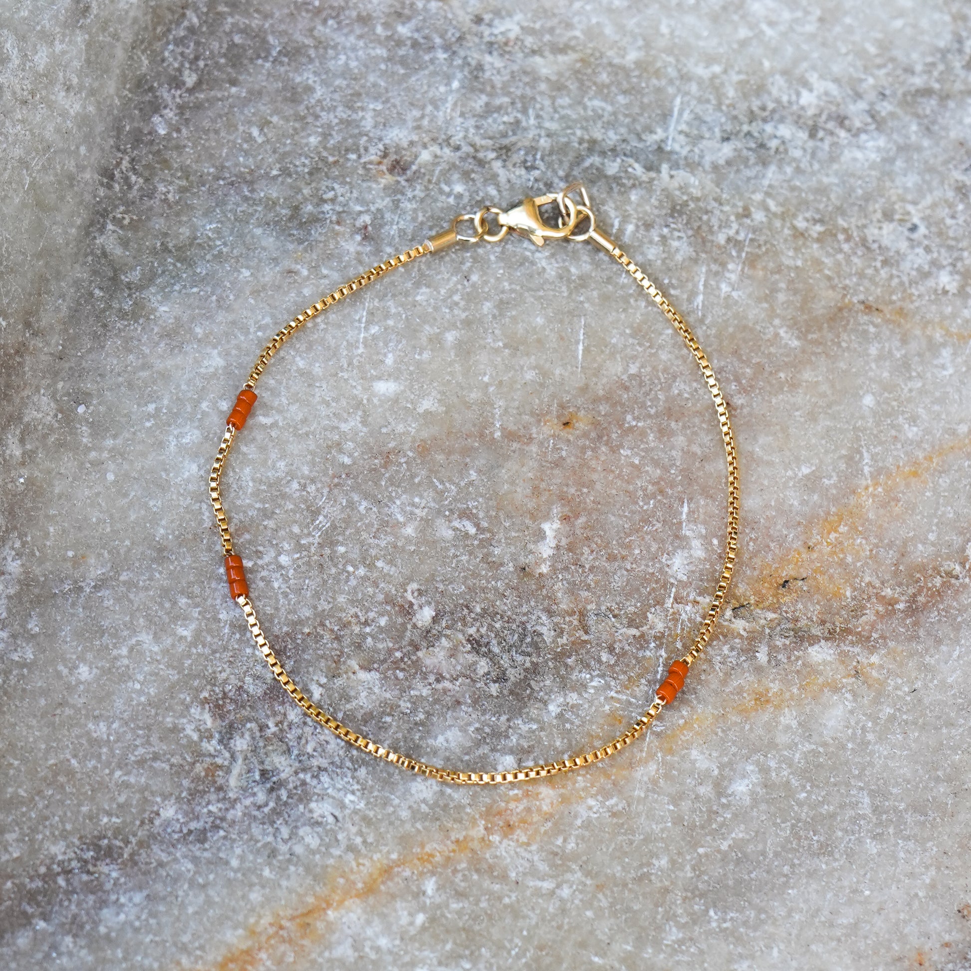 bracelet with gold-fill chain and Japanese seed beads on a stone surface