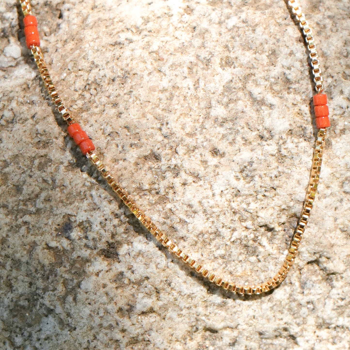 close up of bracelet with gold-fill chain and Japanese seed beads on a boulder