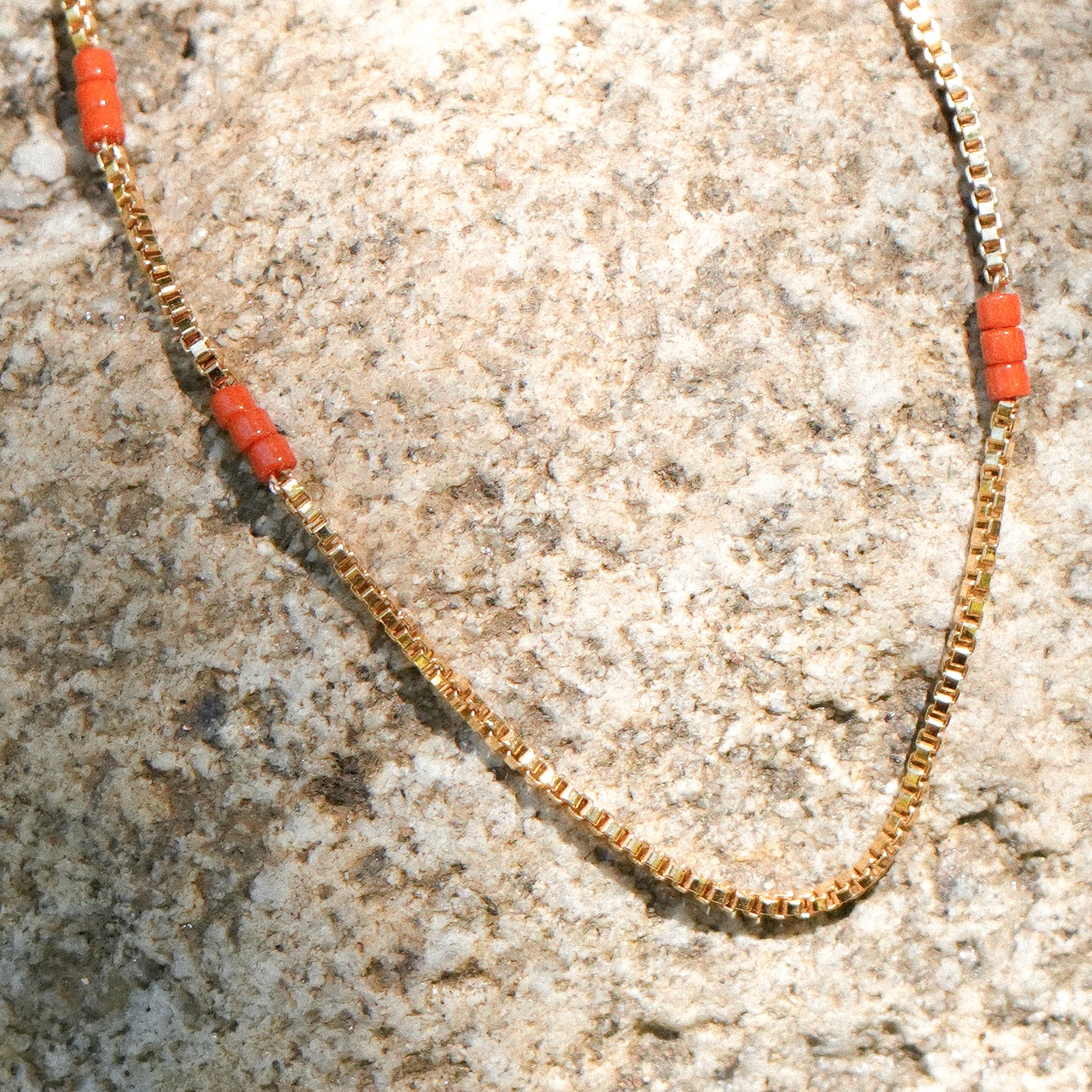 close up of bracelet with gold-fill chain and Japanese seed beads on a boulder