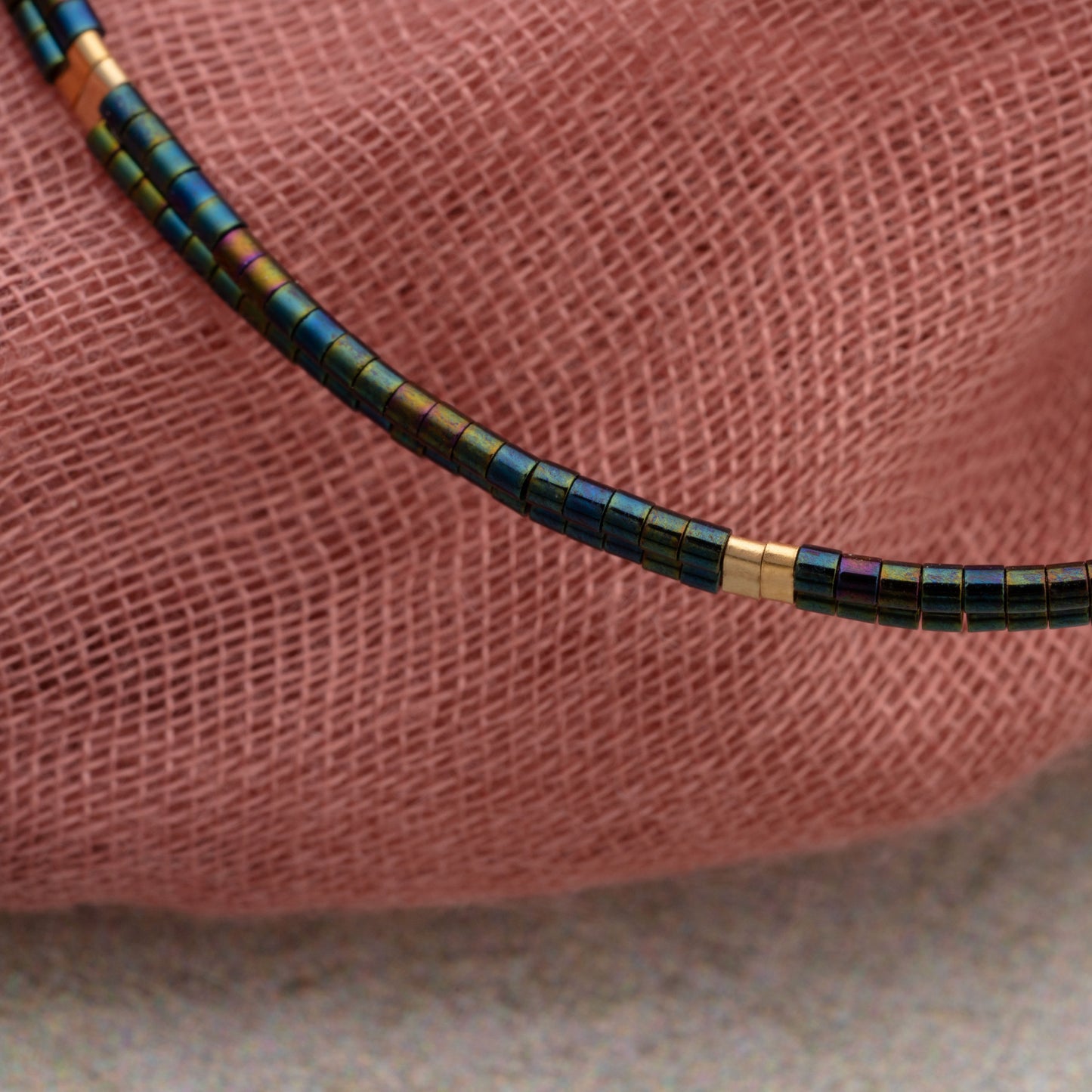 close up of double strand bracelet with iridescent dark teal and green miyuki beads