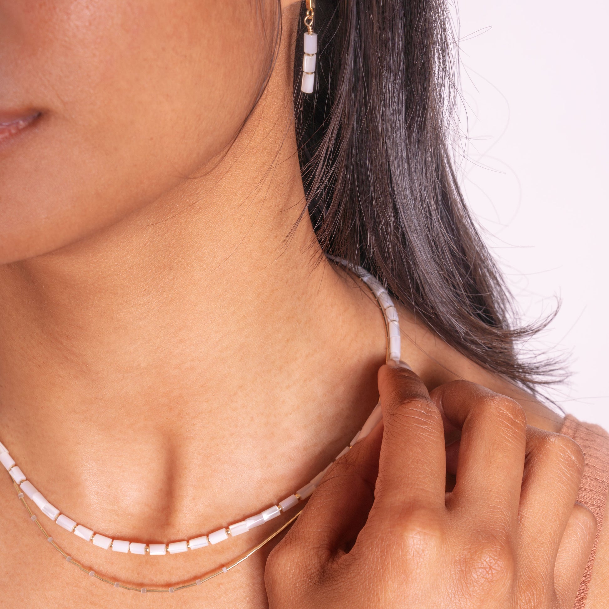 woman wearing earrings and necklace with mother of pearl tube and gold-fill ball beads