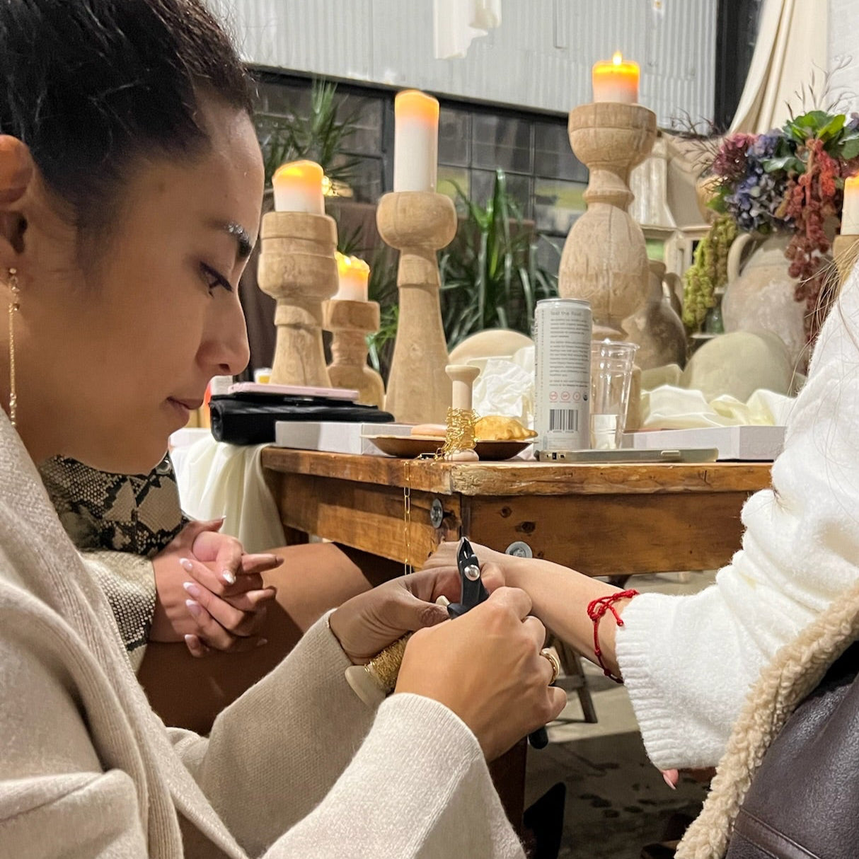 scene of Asian American woman measuring another woman's wrist size in a workshops setting